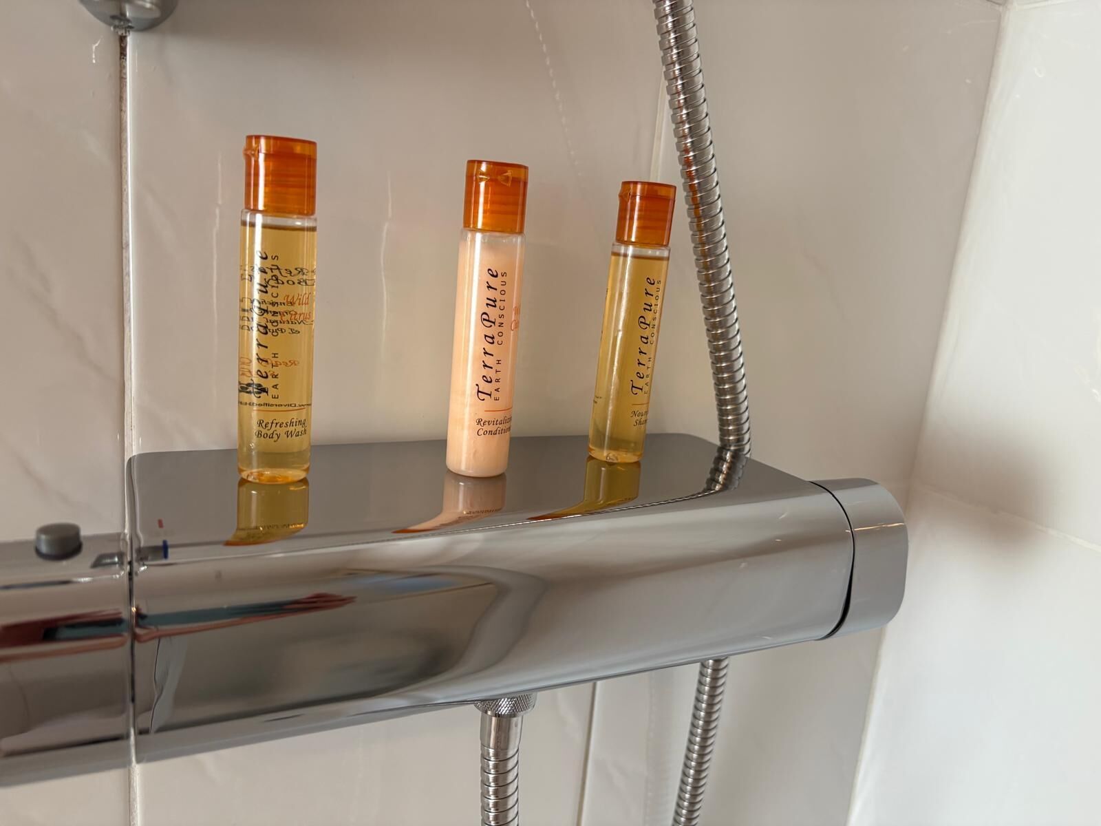 Tres botellas de jabón de cuerpo TerraPure sobre un estante de ducha.
