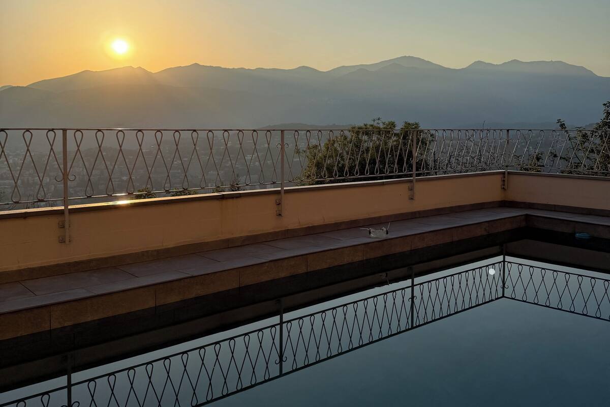 A rooftop terrace with a view of distant mountains during sunset.