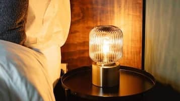 A bed with a pillow, a bedside table with a lamp, and a wooden headboard.