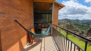 Un balcón con hamaca, paredes de ladrillo y vistas a un paisaje verde.