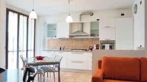 A modern kitchen with white cabinets, a gas stove, and a dining area with a glass table and chairs.