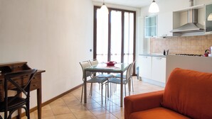 A modern kitchen with a dining table, chairs, and a sofa.
