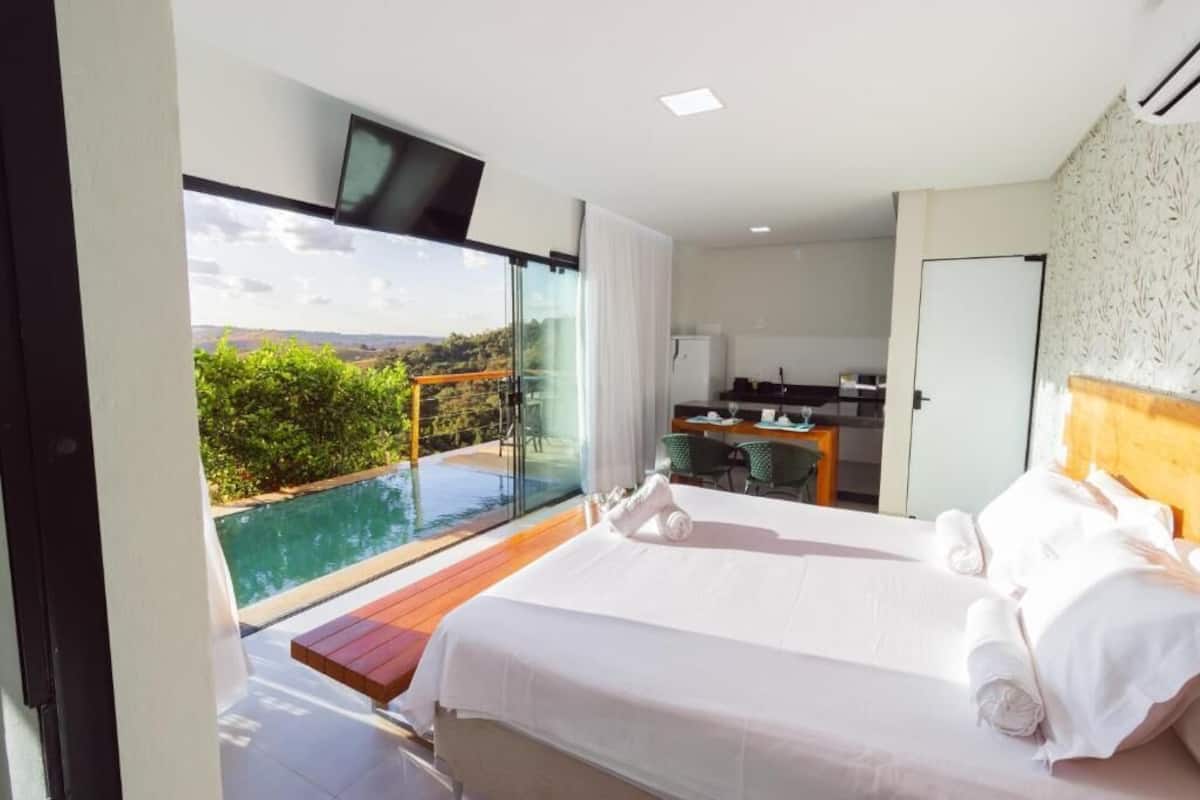 A hotel room with a large bed, a desk, a chair, and a view of a swimming pool.