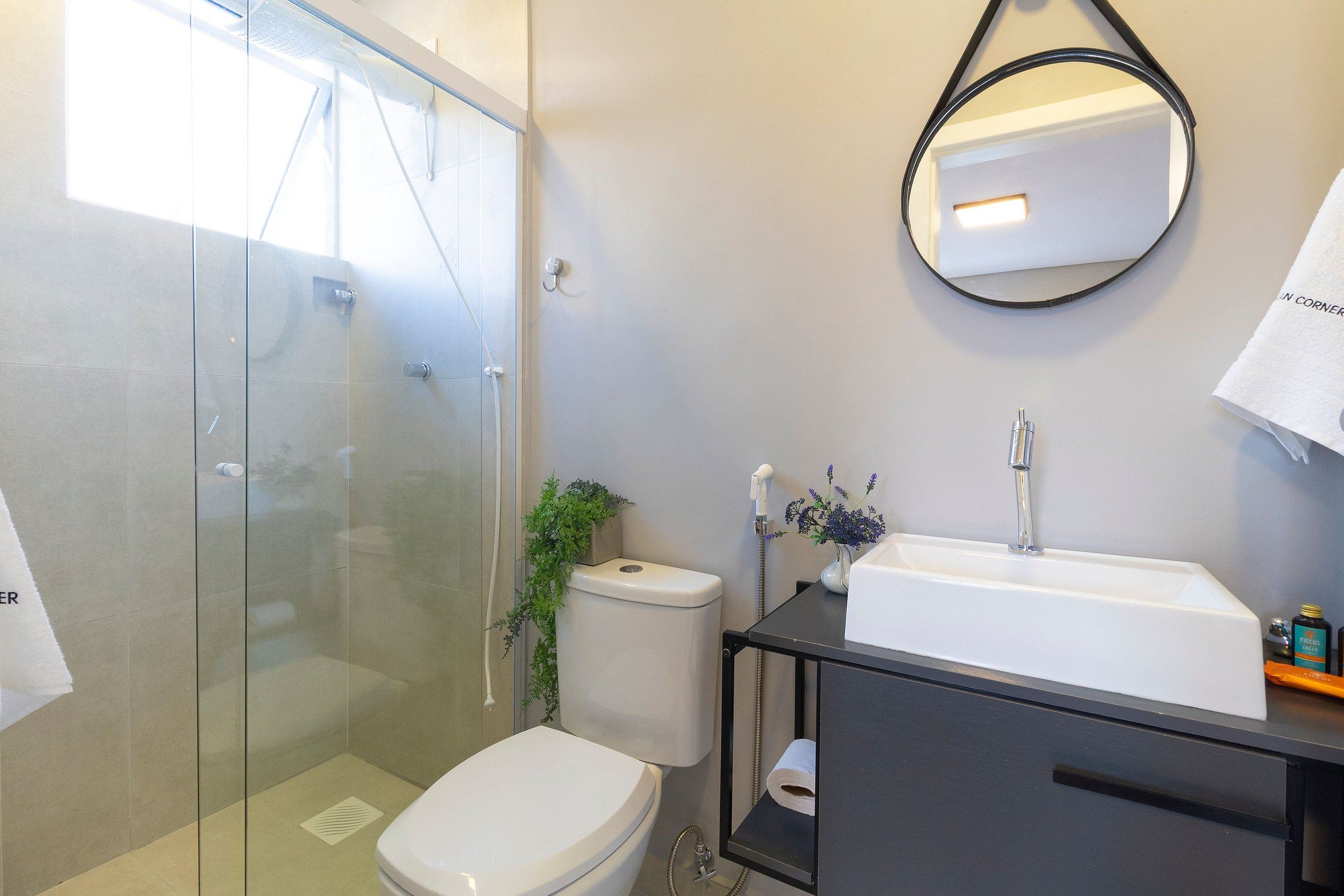 A modern bathroom with a glass-enclosed shower, a white toilet, a black vanity with a sink, and a mirror.