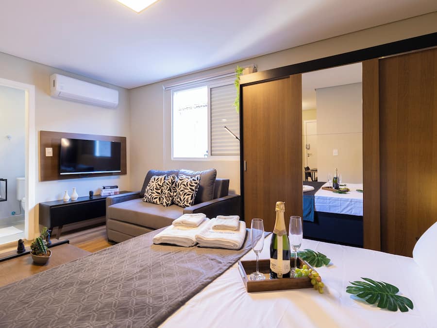 Een moderne hotelkamer met een bed, een televisie, een bank, een bureau en een minibar.