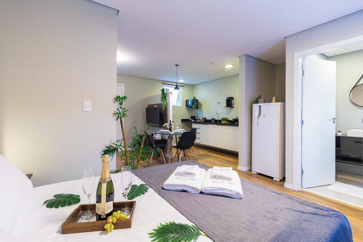 Een hotelkamer met een bed, een ontbijthoek en een kitchenette.