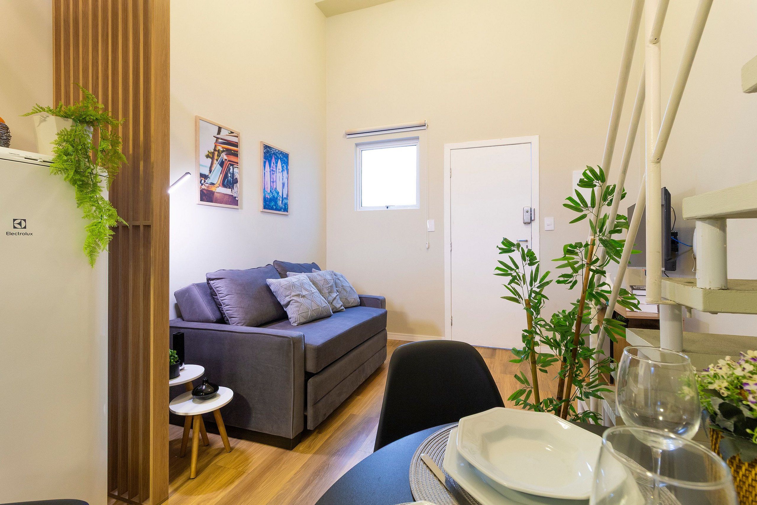 A compact living space with a sofa, a dining table set for two, and a small side table.