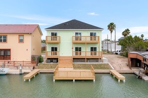Um edifício com vários andares, varandas, um cais e uma área de areia.