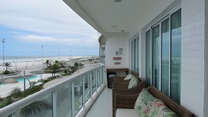 Un balcón con vista a la playa, una piscina y un letrero que indica un restaurante.