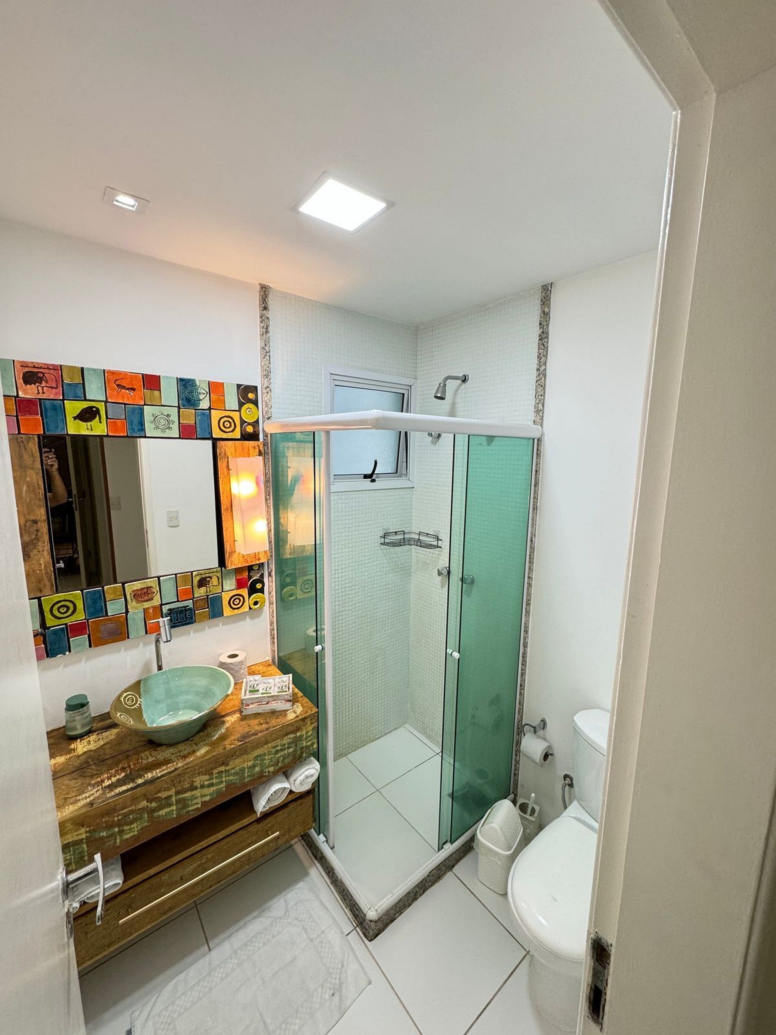 A bathroom with a glass shower enclosure, a sink with a mosaic tile backsplash, and a toilet.
