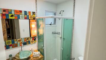 A bathroom with a glass shower enclosure, a sink with a mosaic tile backsplash, and a toilet.