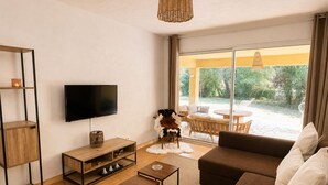 Een moderne woonkamer met een televisie, houten meubels, een bank en uitzicht op een terras.