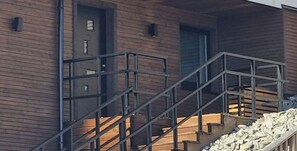Un edificio moderno con fachada de madera, una escalera de metal y una puerta.