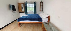 A bedroom with a wooden bed, a television mounted on the wall, a wardrobe, and a window with curtains. - Diamond hill view cottage (Ooty)