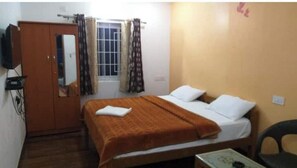 A bedroom with a bed, a wardrobe, a window with curtains, and a desk with a chair. - Diamond hill view cottage (Ooty)