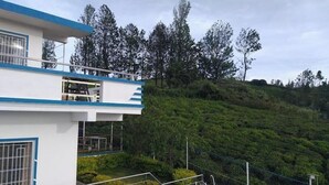 A building with a balcony overlooking a lush green hillside. - Diamond hill view cottage (Ooty)