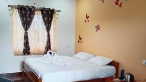 A bedroom with a wooden bed, a nightstand, a small table, and a chair. - Diamond hill view cottage (Ooty)