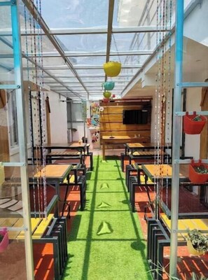 A children's play area with tables and chairs, a green carpet, and hanging decorations. - Diamond hill view cottage (Ooty)