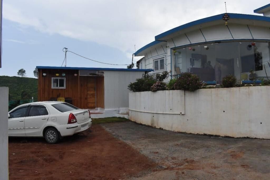 Una casa de un piso con techo azul, fachada blanca y puerta de garaje visible.
