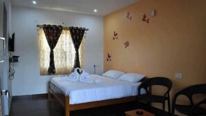 Un dormitorio con una cama, dos sillas, una mesita y una pared decorada con adhesivos de mariposas.