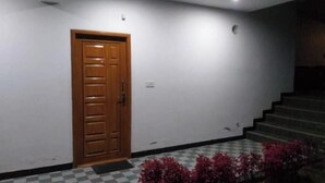 Un pasillo con puerta de madera, una escalera y suelo a cuadros.