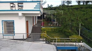 A building with a staircase leading to a covered outdoor area. - Kathiresan's Diamond hill view cottage (Ooty)