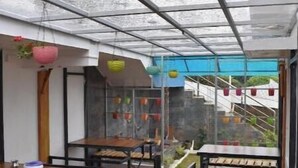 An indoor patio area with tables and chairs, a glass ceiling, and a view of the outside. - Kathiresan's Diamond hill view cottage (Ooty)
