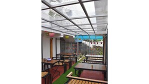 En indendørs patio med borde og stole, et glasloft og udsigt til det fri.