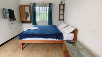 Un dormitorio con cama de madera, televisor montado en la pared, armario y ventana con cortinas.