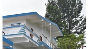 A multi-story building with balconies, a staircase, and a statue in the foreground. - Kathiresan's Diamond hill view cottage (Ooty)