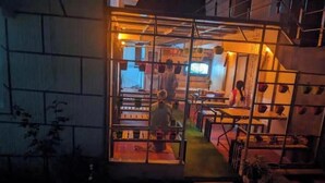A cozy restaurant with a glass partition, outdoor seating, and a staircase leading to the entrance. - Kathiresan's Diamond hill view cottage (Ooty)