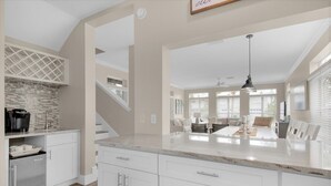 A spacious kitchen with white cabinets, a granite countertop, and a built-in range hood.