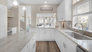 A modern kitchen with white cabinets, a marble countertop, and a built-in sink.
