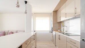 Cozinha moderna com bancada comprida, armários de madeira e iluminação pendente.