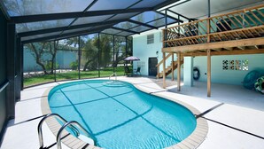 Ein Schwimmbecken mit Glasveranda, Holzterrasse und Blick ins Freie.