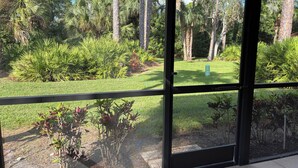 A view through a glass door of a well-maintained garden with various plants and trees.