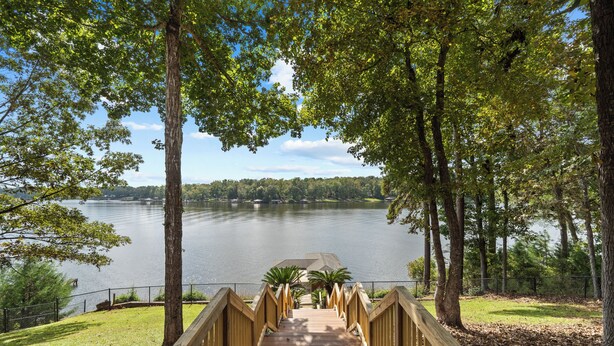 Una terraza de madera que da a un lago, con vistas al agua y a los árboles circundantes.