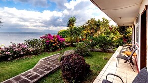 A balcony with a view of the sea, surrounded by lush greenery and vibrant flowers. - Hotel Sak'cari El Amanecer (San Pedro La Laguna)