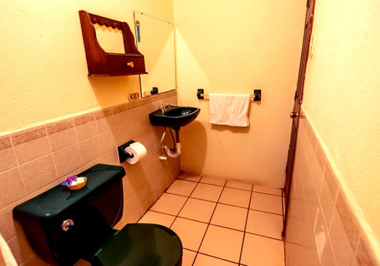 A small bathroom with a toilet, sink, and mirror.