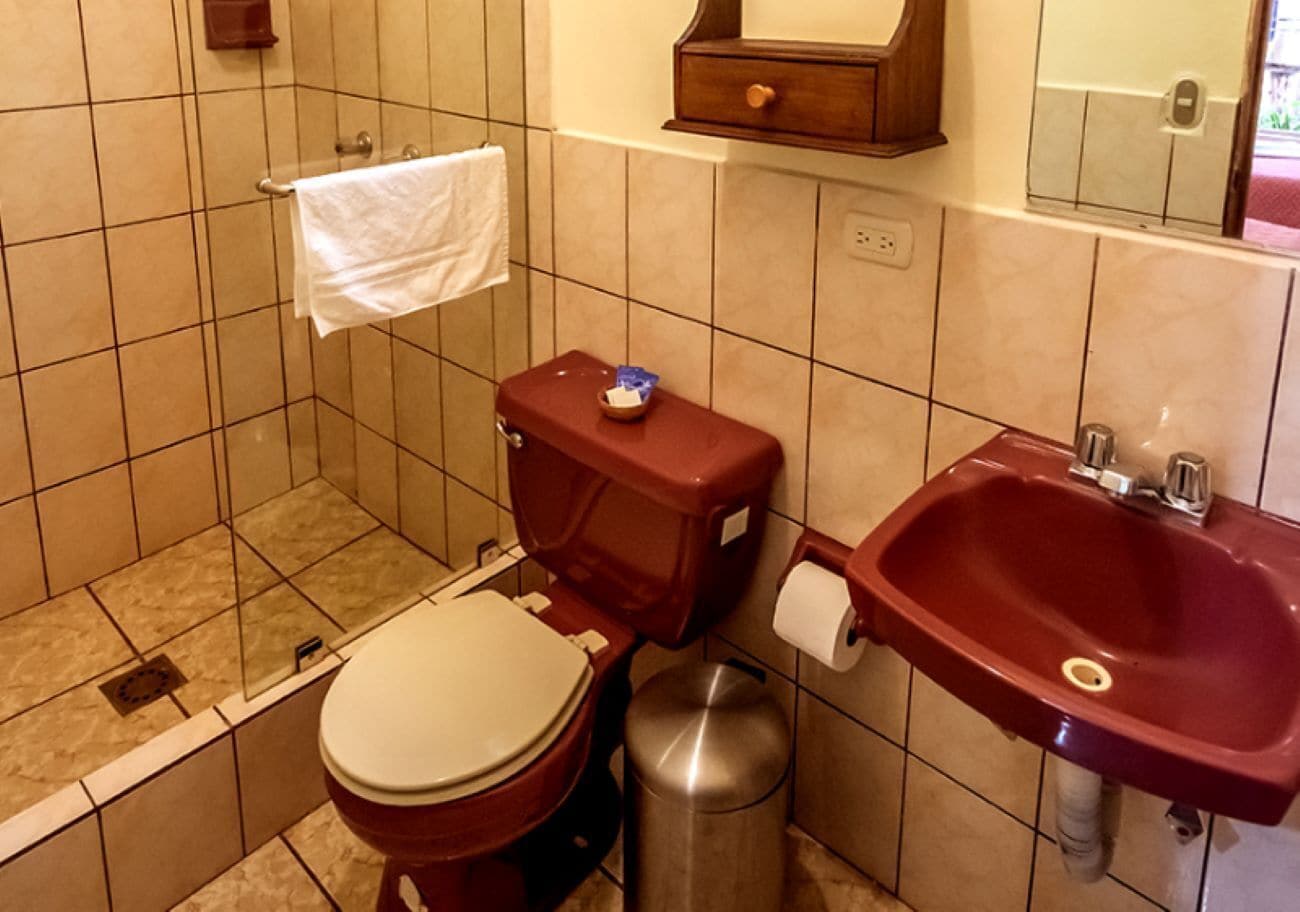 A bathroom with a toilet, sink, and trash can.