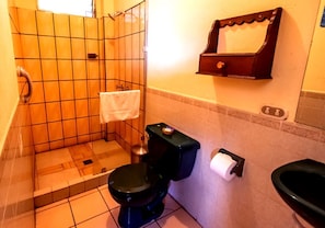 A bathroom with a black toilet, a shower area, and a towel rack. - Hotel Sak'cari El Amanecer (San Pedro La Laguna)