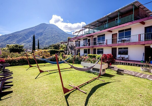 A hotel with a two-story structure, a balcony on the upper floor, and a view of a mountain in the background.