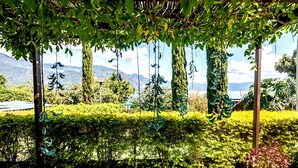 A garden with a pergola, neatly trimmed hedges, and a view of mountains in the background. - Hotel Sak'cari El Amanecer (San Pedro La Laguna)