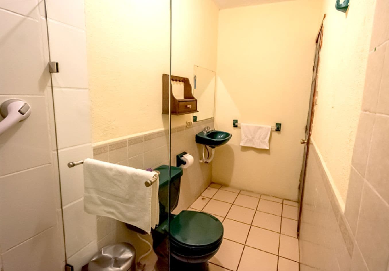 A small bathroom with a toilet, sink, and shower.