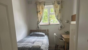 A small, neatly arranged bedroom with a bed, a desk, and a chair. - Homely 2-bed Apartment - Sleeps 3 & Parking (Walton-on-Thames)
