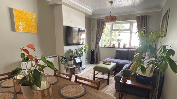 A living room with a sofa, dining table, and various plants. - Homely 2-bed Apartment - Sleeps 3 & Parking (Walton-on-Thames)
