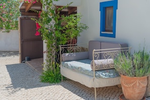 A small outdoor seating area with a metal bench, a potted plant, and a wall-mounted window. - Country House 'Perfect To Relax' with Private Terrace, Wi-Fi and Air Conditioning (Algoz)