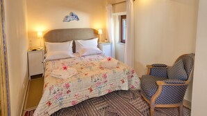 Une chambre à coucher comprenant un lit, une chaise, une table de chevet et un climatiseur fixé au mur.