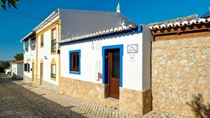 Un bâtiment traditionnel avec un mur en pierre, un toit en tuiles et une porte bleue.