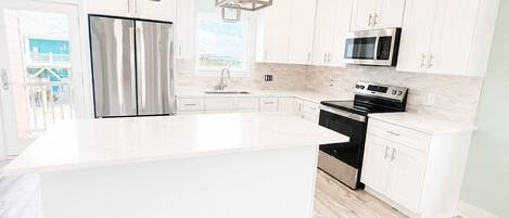 A modern kitchen with white cabinetry, stainless steel appliances, and a large island.